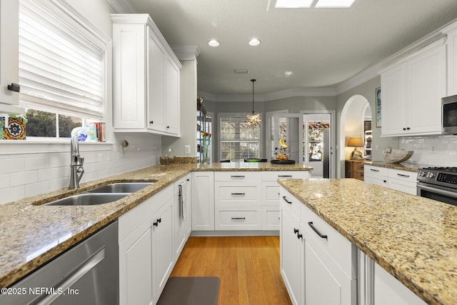 kitchen with stainless steel appliances, a sink, white cabinetry, light wood-style floors, and crown molding