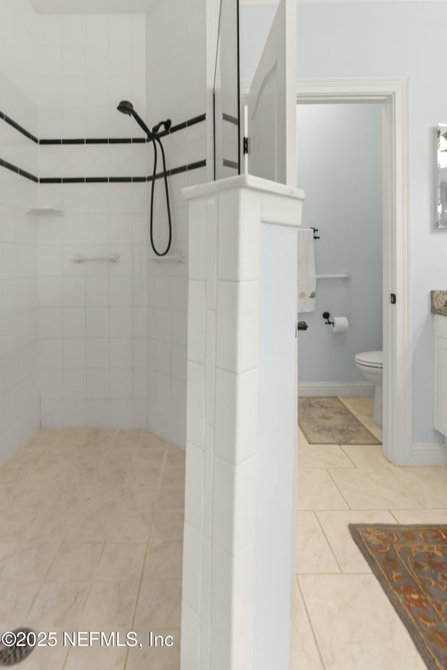 bathroom featuring vanity, tiled shower, tile patterned floors, and toilet