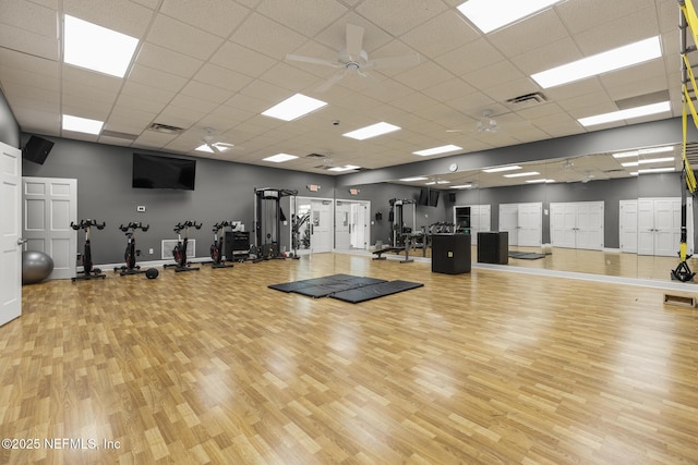 exercise room with visible vents, a drop ceiling, baseboards, and wood finished floors