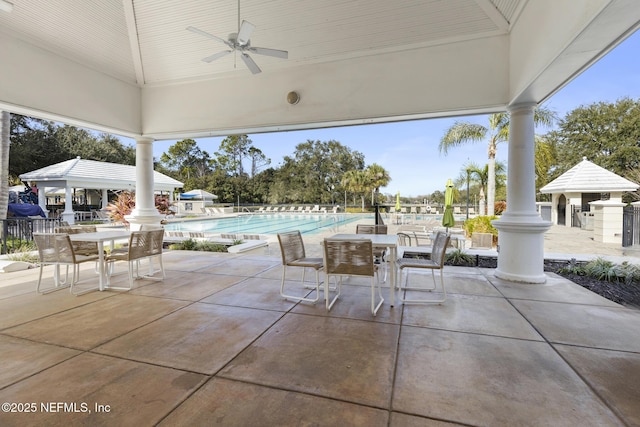 view of patio with fence, a community pool, and ceiling fan