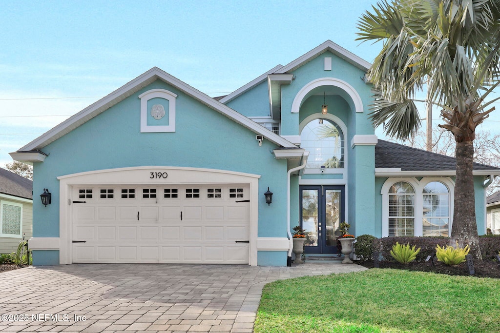 view of front of home featuring a garage, a front lawn, and french doors