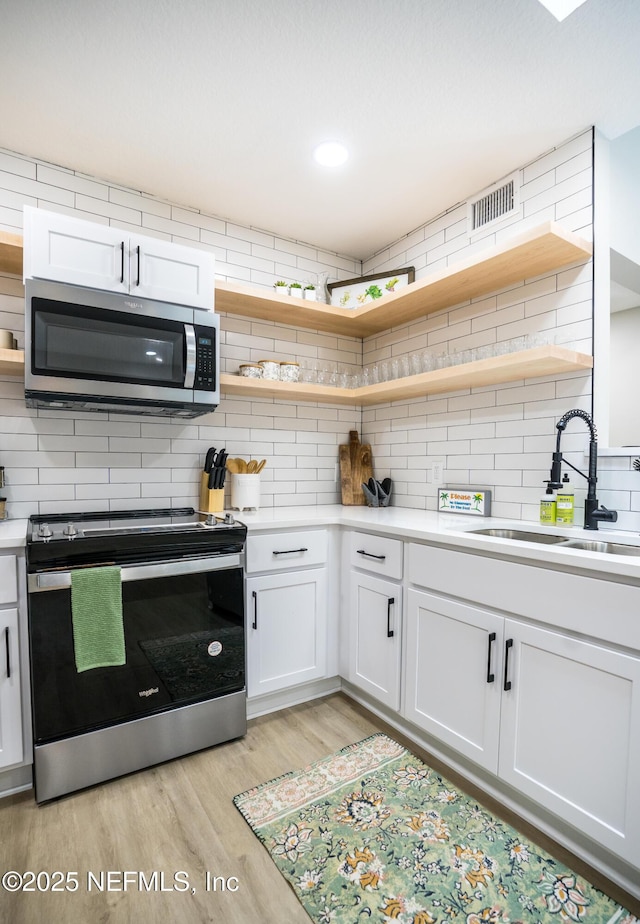 kitchen with white cabinetry, appliances with stainless steel finishes, sink, and backsplash