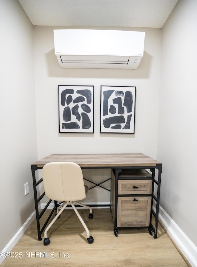 office space with a wall unit AC and light hardwood / wood-style floors