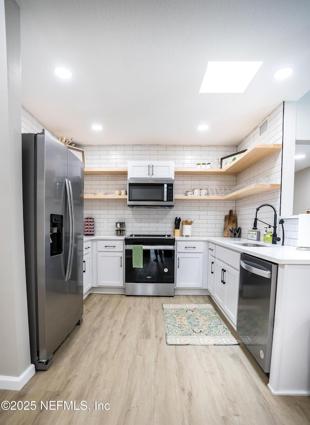 kitchen with tasteful backsplash, appliances with stainless steel finishes, sink, and white cabinets