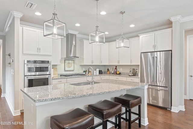 kitchen featuring white cabinetry, stainless steel appliances, sink, and wall chimney range hood