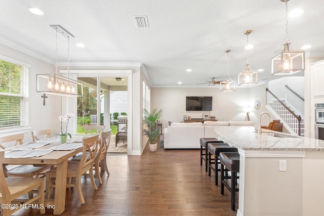 dining space featuring crown molding, dark hardwood / wood-style flooring, sink, and a wealth of natural light