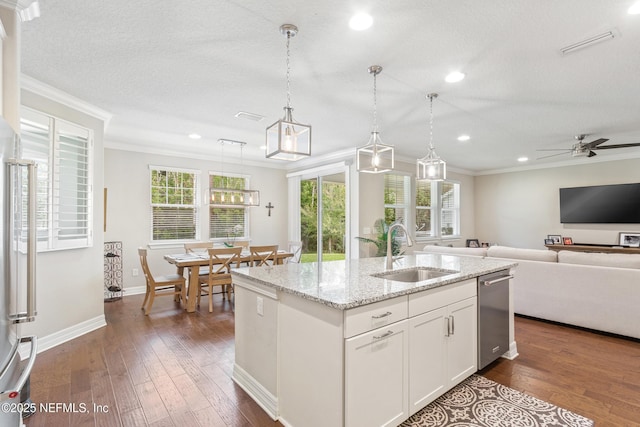 kitchen with pendant lighting, sink, crown molding, an island with sink, and white cabinets