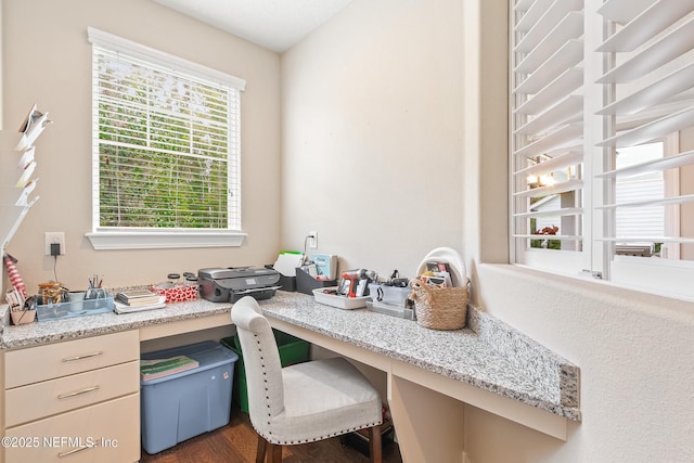 home office featuring plenty of natural light, dark hardwood / wood-style flooring, and built in desk