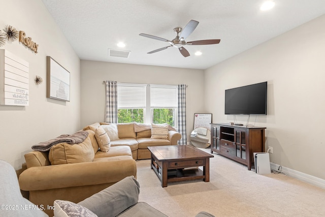 carpeted living room featuring ceiling fan and a textured ceiling