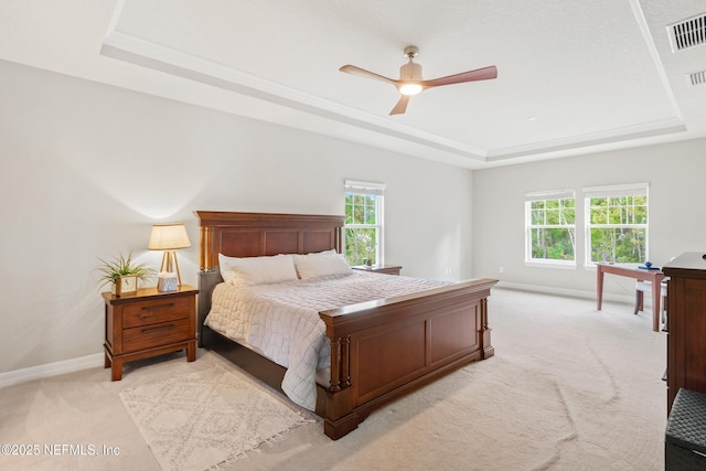 carpeted bedroom featuring ceiling fan, a tray ceiling, and multiple windows