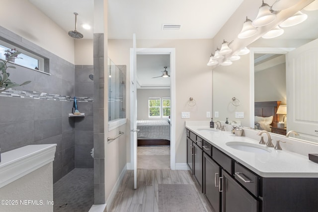 bathroom featuring vanity, ceiling fan, and a tile shower