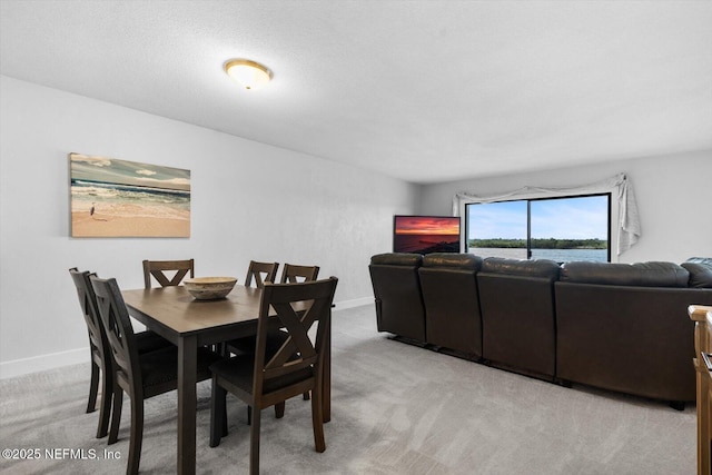 dining space featuring light carpet and a textured ceiling