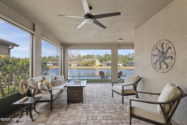 sunroom / solarium featuring plenty of natural light, a ceiling fan, and a water view