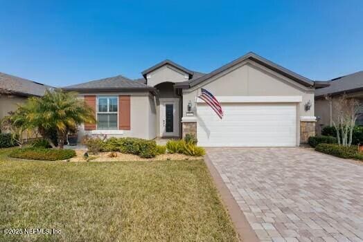 single story home featuring a front lawn, decorative driveway, a garage, and stucco siding