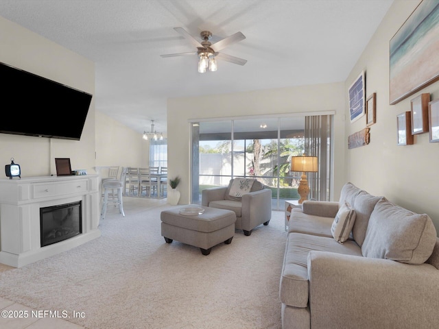 carpeted living room with ceiling fan with notable chandelier