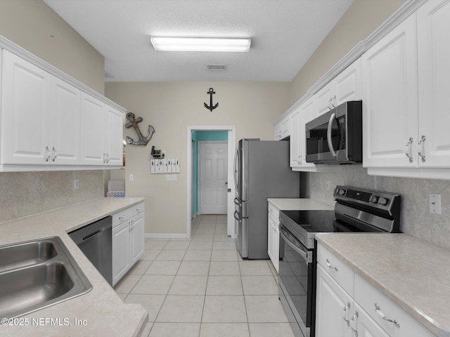 kitchen featuring light tile patterned flooring, appliances with stainless steel finishes, and white cabinets