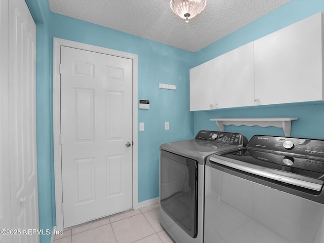 washroom featuring cabinets, washer and dryer, light tile patterned floors, and a textured ceiling