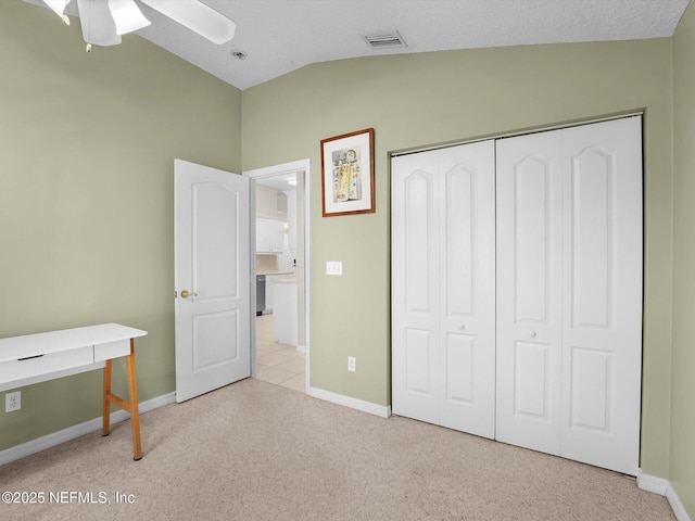 bedroom with vaulted ceiling, light colored carpet, ceiling fan, and a closet