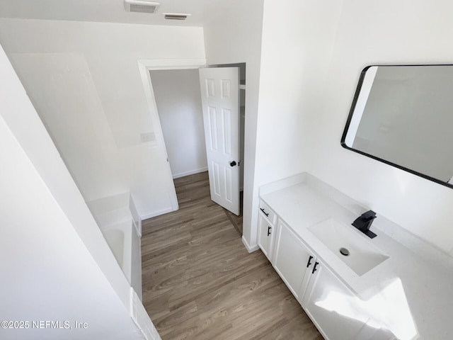 interior space with vanity, a bathtub, and hardwood / wood-style flooring