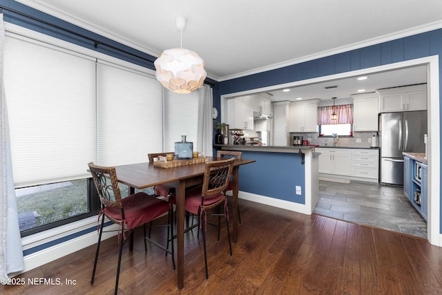 dining space with crown molding, dark hardwood / wood-style flooring, and sink