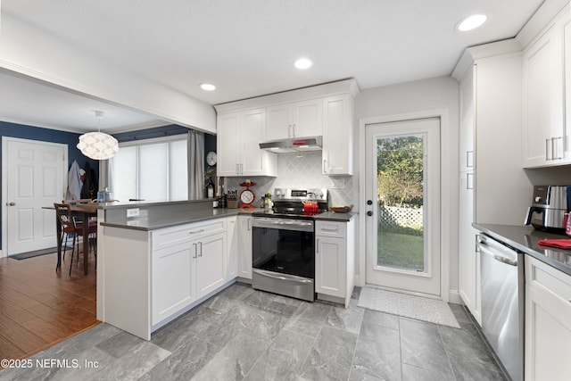 kitchen with white cabinetry, backsplash, hanging light fixtures, kitchen peninsula, and stainless steel appliances