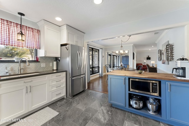 kitchen featuring wood counters, sink, pendant lighting, and stainless steel appliances