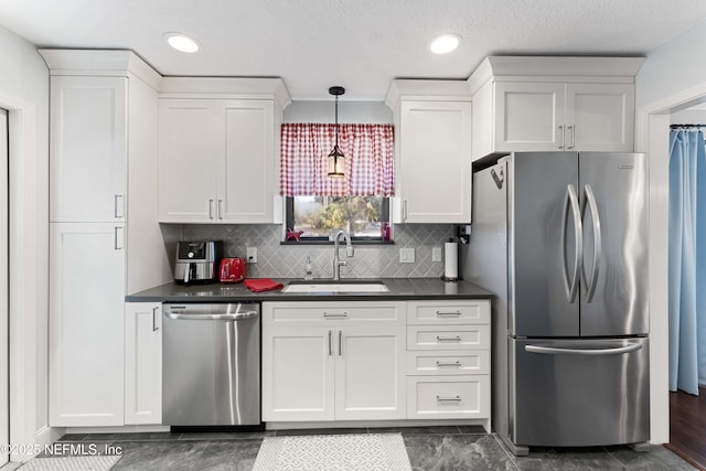 kitchen featuring appliances with stainless steel finishes, sink, white cabinets, decorative backsplash, and hanging light fixtures