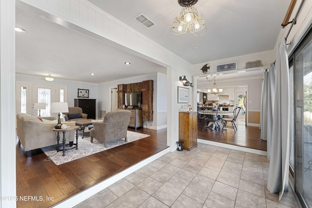 living room with an inviting chandelier, light tile patterned floors, and crown molding