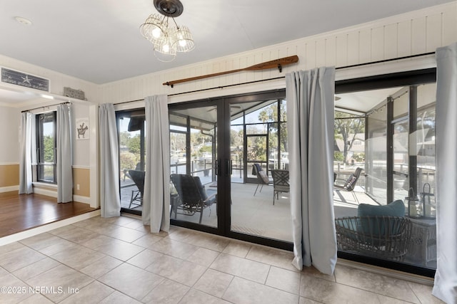 entryway featuring light tile patterned floors, crown molding, french doors, and a chandelier