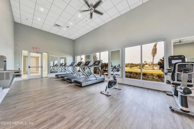 workout area featuring a ceiling fan, visible vents, a high ceiling, and wood finished floors