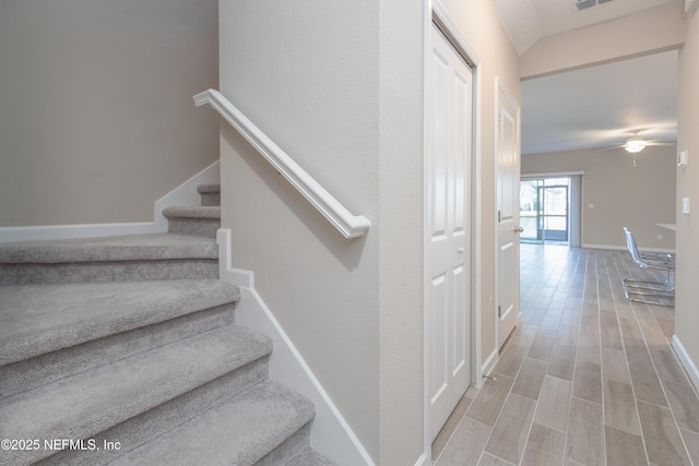 stairway featuring a ceiling fan, visible vents, baseboards, and wood finished floors