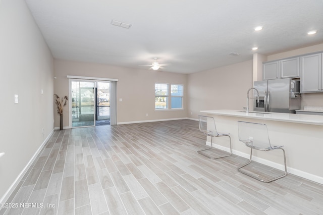 kitchen with light wood-type flooring, stainless steel fridge, light countertops, and gray cabinetry