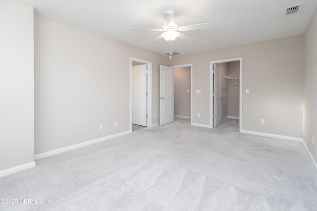 unfurnished bedroom featuring a spacious closet, visible vents, and baseboards