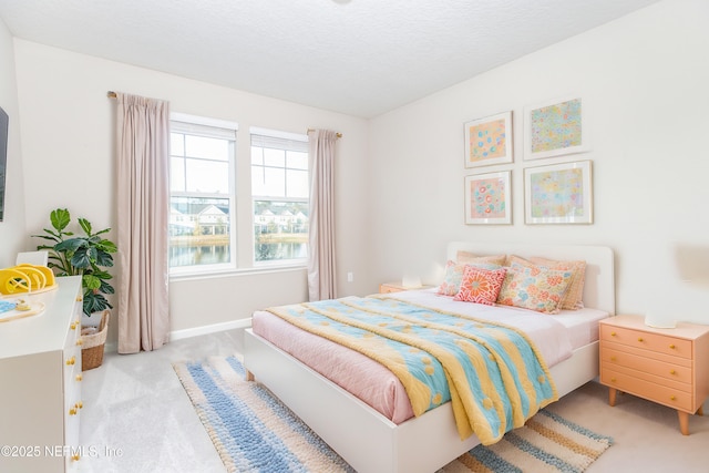 bedroom with baseboards, a textured ceiling, and light colored carpet