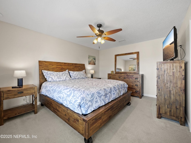 bedroom with a textured ceiling, light colored carpet, and ceiling fan