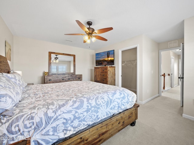 bedroom with a spacious closet, light carpet, ceiling fan, and a closet