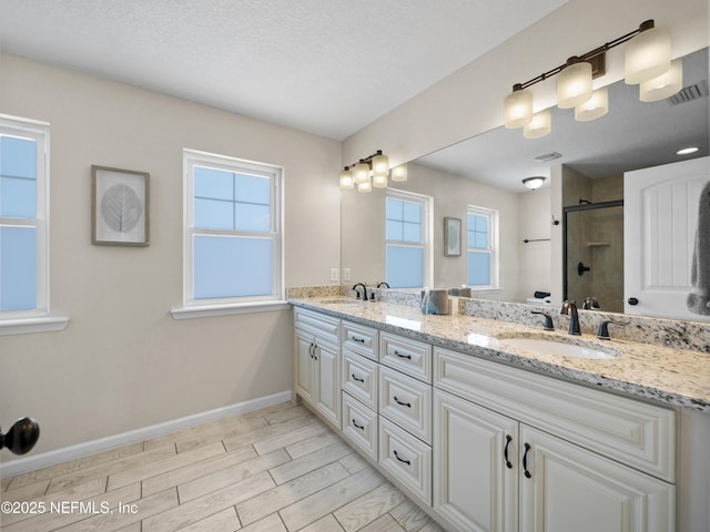 bathroom with vanity, a textured ceiling, and walk in shower