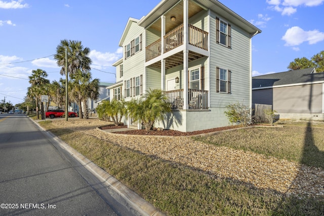 view of side of home featuring a yard and a balcony