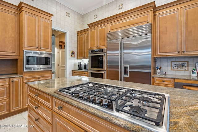 kitchen with stone countertops, built in appliances, light tile patterned floors, ornamental molding, and decorative backsplash