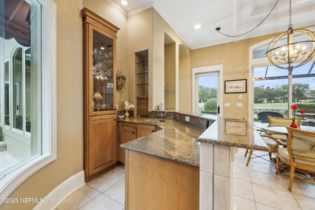 bar with light tile patterned floors, sink, dark stone countertops, hanging light fixtures, and an inviting chandelier