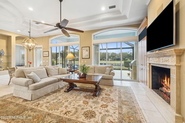 living room with a tray ceiling, a premium fireplace, and a healthy amount of sunlight