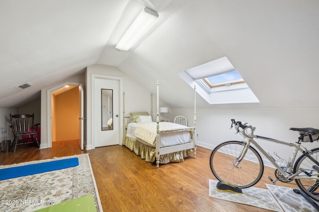 bedroom with wood-type flooring and lofted ceiling with skylight