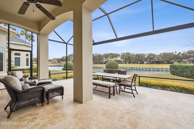 view of patio / terrace featuring ceiling fan, a water view, and glass enclosure