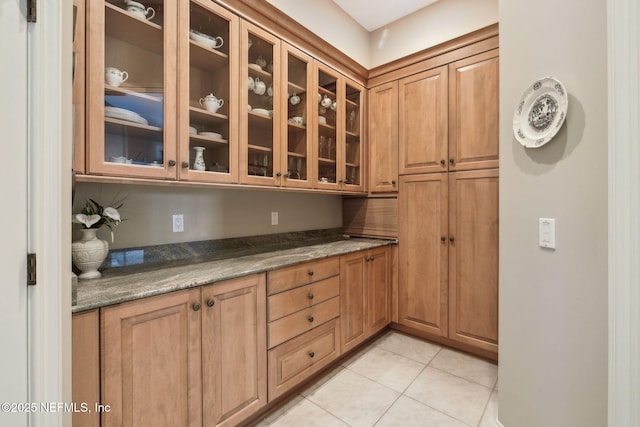 kitchen with light tile patterned floors and dark stone countertops