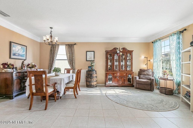 tiled dining space with ornamental molding, a notable chandelier, and a textured ceiling