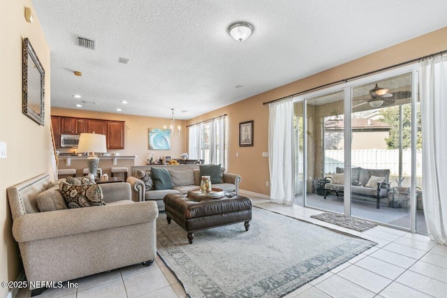 tiled living room featuring a notable chandelier and a textured ceiling