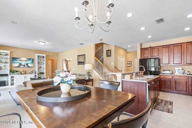 tiled dining room with sink, a notable chandelier, and a textured ceiling