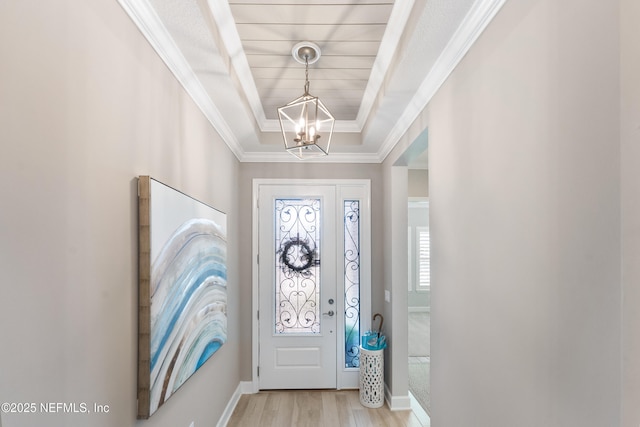 foyer featuring ornamental molding, a notable chandelier, light hardwood / wood-style floors, and a tray ceiling