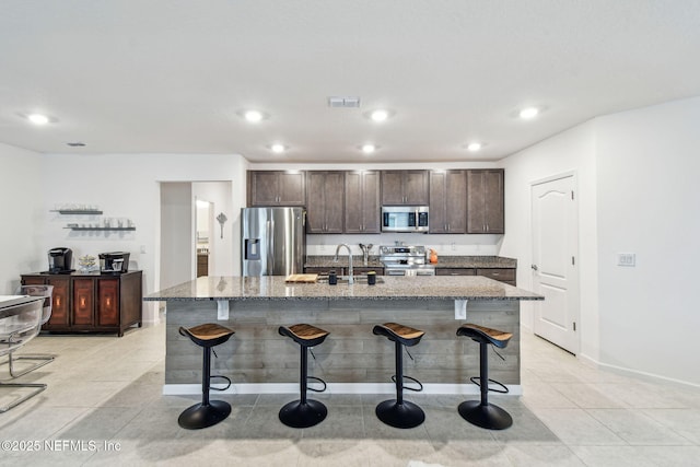 kitchen with stainless steel appliances, a kitchen island with sink, and a kitchen breakfast bar