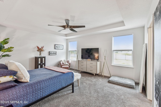 carpeted bedroom featuring a tray ceiling and ceiling fan